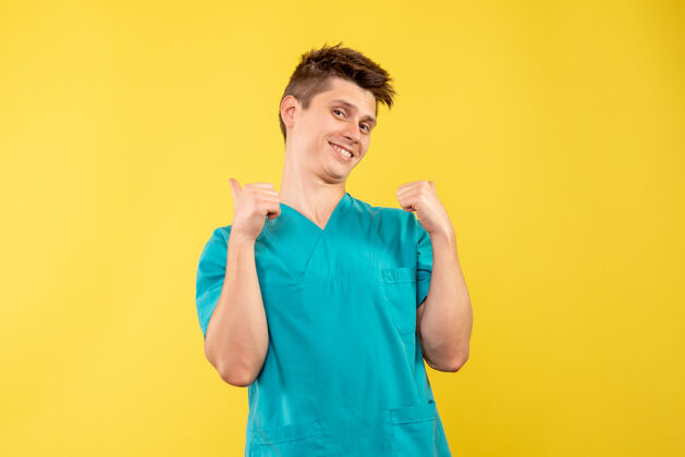 套装正面图黄色背景上穿着医疗服的年轻男医生微笑医学人物