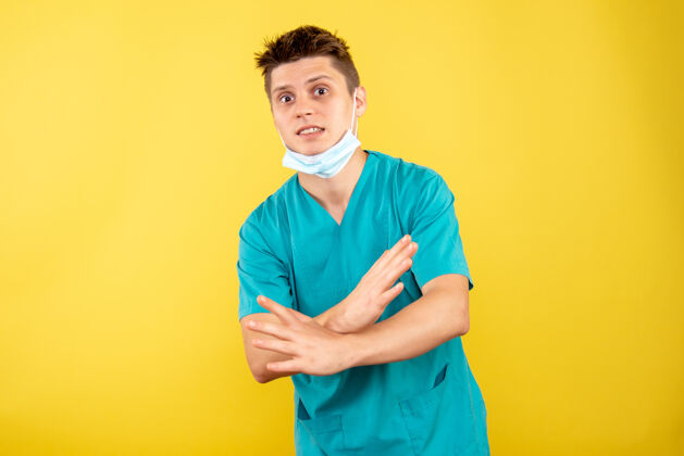 绝育正面图身着医疗服的年轻男医生 黄色背景上有无菌面罩医学面具肖像
