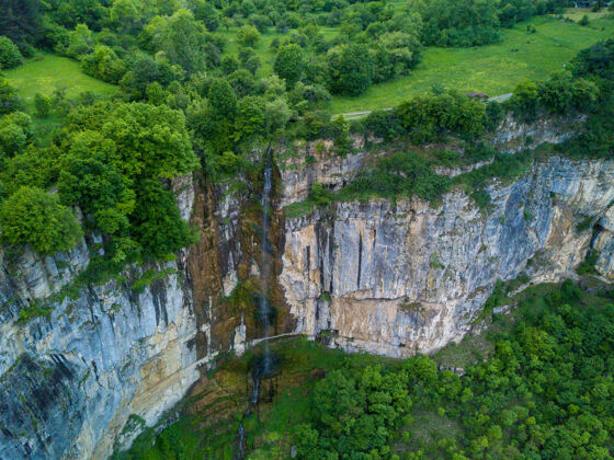 岩石空中拍摄的瀑布在美丽的山上覆盖着树木环境水石头