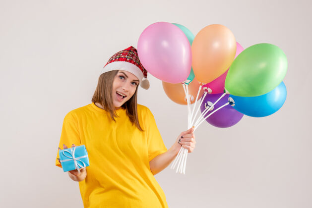 礼物手持小礼物和白色气球的年轻女性吹乐趣女人