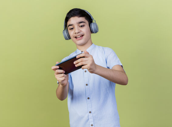 手机兴奋的年轻白人男孩戴着耳机在手机上玩游戏孤立的背景与复制空间年轻玩兴奋