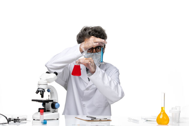 男性正面图穿着特殊套装的中年科学家坐着拿着装有解决方案的烧瓶化学观点前面