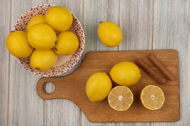 棒整只柠檬放在碗里的俯视图 柠檬被隔离在木制的厨房板上 肉桂棒放在灰色的木墙上厨房配料木头