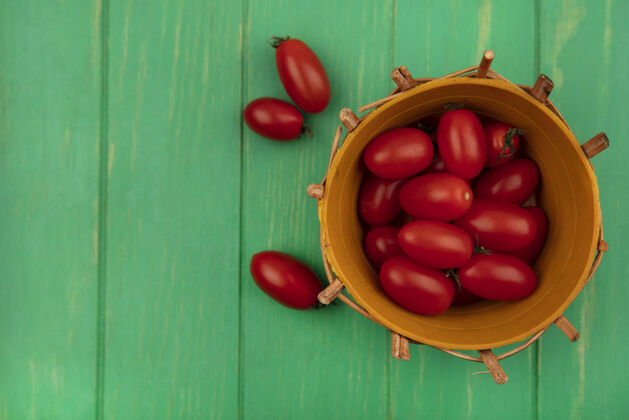 木材新鲜的红色李子西红柿在一个绿色的木制墙壁与复制空间桶顶视图桶农业有机