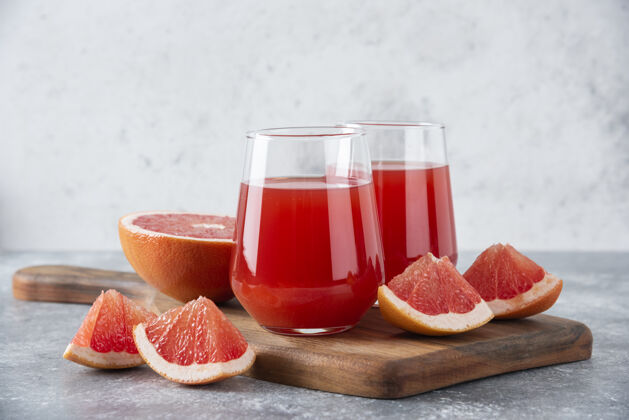 美食在木板上放一杯新鲜的柚子汁和水果片果汁健康柑橘