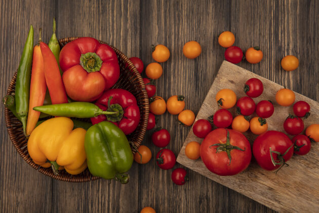 顶部顶视图新鲜的西红柿孤立在一个木制的厨房板上 五颜六色的辣椒放在木桶上的木墙上食品农业木材
