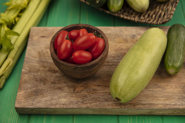 农场新鲜蔬菜的俯视图 如黄瓜西葫芦放在木制的厨房板上 李子西红柿放在木制的碗上 芹菜被隔离在绿色的木墙上营养西葫芦观点