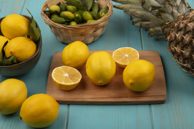 菠萝新鲜的柠檬被隔离在木制的厨房板上 柠檬被隔离在蓝色的木墙上 菠萝被隔离在碗上食物切片柑橘