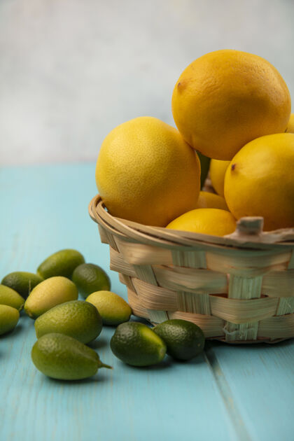 水果一个桶上的新鲜柠檬的侧视图 蓝色的木墙上孤立着金盏花木材切片桶