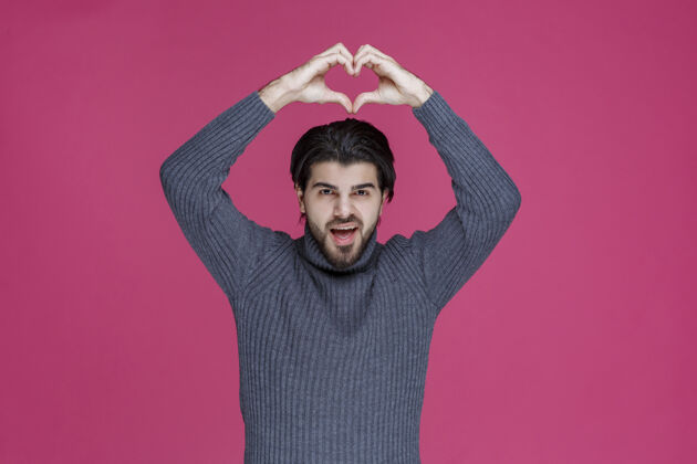 模特穿灰色毛衣的男人用手做心形标志积极人体模特姿势