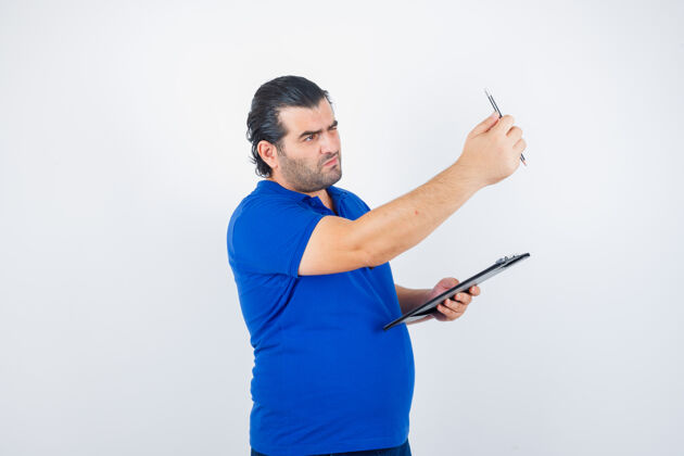 游戏中年男子穿着马球衫拿着剪贴板 看着铅笔 目光集中前视图前面互联网商务
