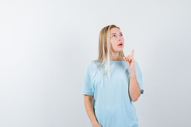 女性穿着蓝色t恤的金发女孩用食指向上指 向上看 神情沉思 俯视前方人天空手指