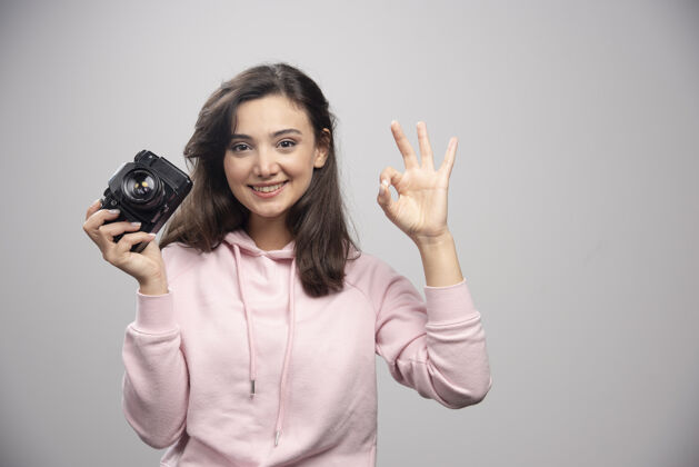 休闲女摄影师拿着相机 做着“ok”的手势肖像可爱人