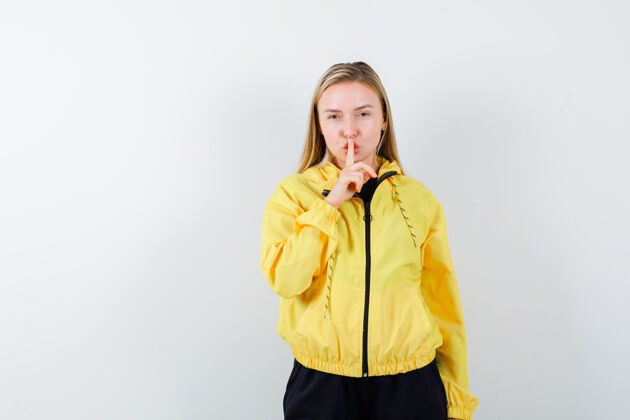 面部身穿黄色夹克和裤子的年轻女士表现出沉默的姿态 仔细地看着前方快乐成人护理