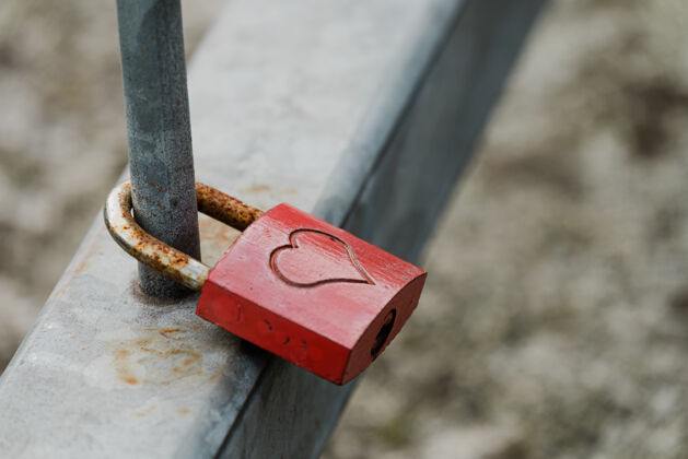 金属一个金属挂锁的特写镜头 心形挂在篱笆上锁安全挂锁