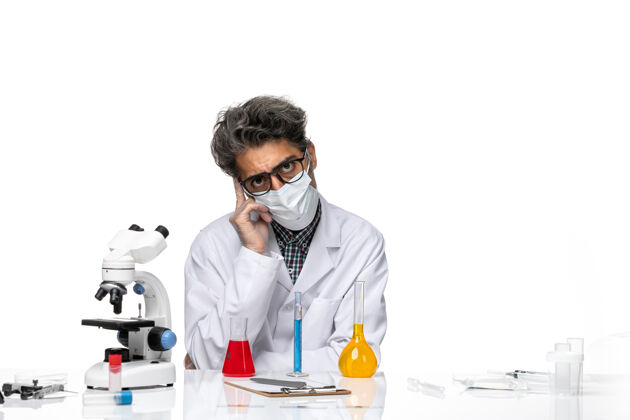 医学正面图中年科学家穿着特殊的西装坐着解决方案和思考人实验室外套实验室