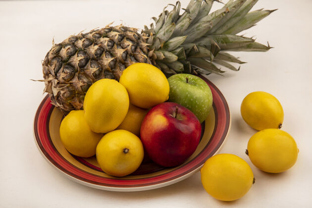 人多汁水果的俯视图 如菠萝 五颜六色的苹果和柠檬放在一个碗里 柠檬被隔离在白色的墙上膳食农业顶部