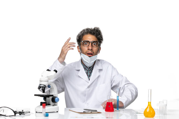 实验室正面图身着特殊套装的中年科学家围坐在桌子旁 拿着解决方案周围男性前面