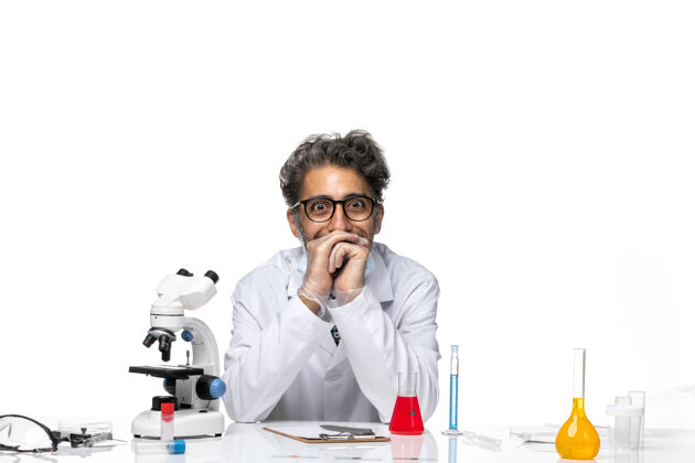 实验正面图穿着特殊白色西装的中年科学家围坐在桌子旁 拿着解决方案观点科学微笑