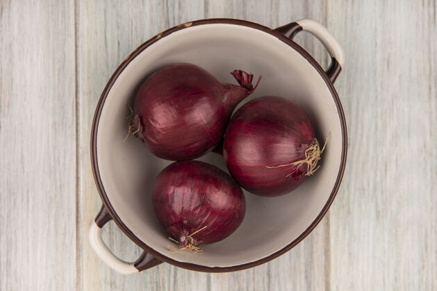 木头健康和新鲜的红洋葱在一个灰色的木墙上碗顶视图薯条饭洋葱