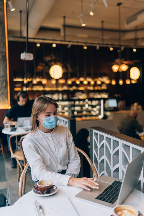 距离美女戴着医用面罩用笔记本电脑上班检疫感染自助餐厅