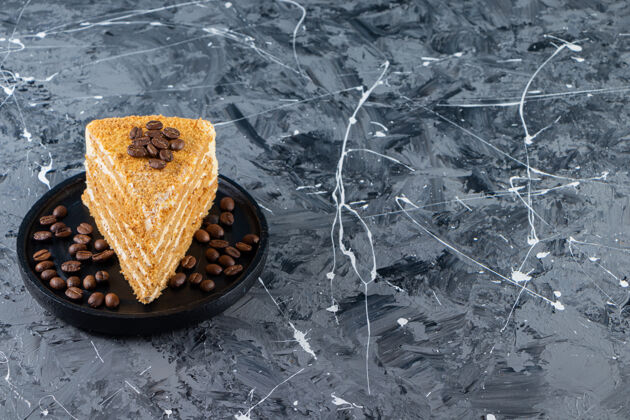 美味把一片分层的蜂蜜蛋糕和咖啡豆放在大理石桌上蜂窝姜饼美食