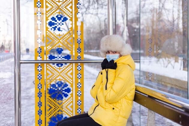 换乘在寒冷的日子里 一个穿着冬衣的女人在公共汽车站等公共汽车车站电车等待