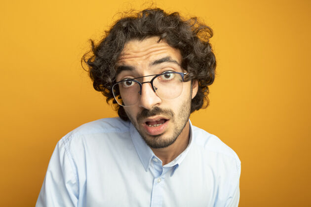表情戴着眼镜的年轻帅哥的特写镜头被隔离在橙色的墙上眼镜特写穿着