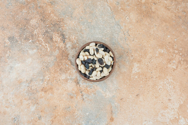 小葡萄干在大理石背景上放满葡萄干和坚果的小木碗食物可口木头