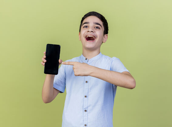人印象深刻的小男孩拿着手机指着前面孤立的橄榄绿墙上姿势手机年轻人