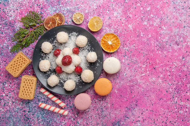 可口美味的椰子糖甜球的顶视图 浅粉色的表面上有麦卡龙顶视图糖麦卡龙