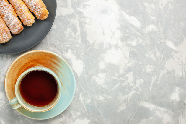 马克杯糖粉百吉饼的俯视图美味的面团和一杯茶在白色的表面咖啡面团食物