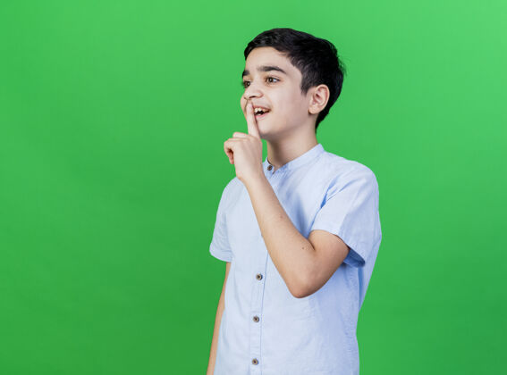 沉默印象深刻的小男孩站在侧视图直看做沉默的手势隔离在绿色的墙壁上印象直人