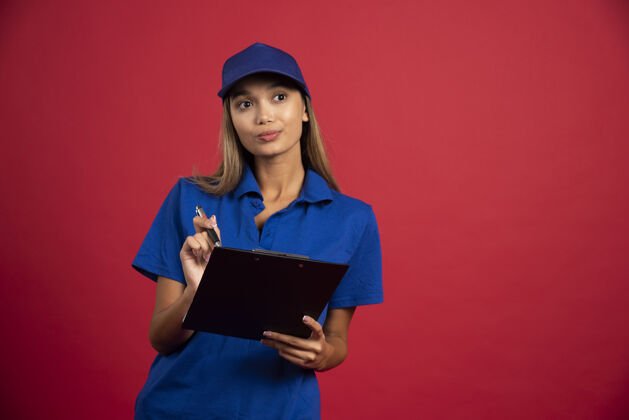 指向穿着蓝色制服的年轻女子拿着剪贴板和铅笔摆姿势人类制服剪贴板