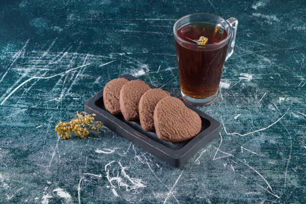 美味巧克力心饼干和一杯红茶放在石头桌上茶饼干马克杯