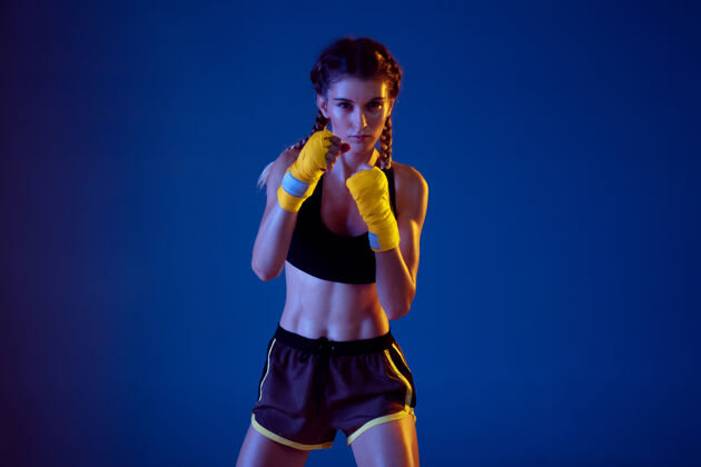 运动服在霓虹灯的蓝色背景下 适合穿运动服拳击的白人女性霓虹灯女人身体护理