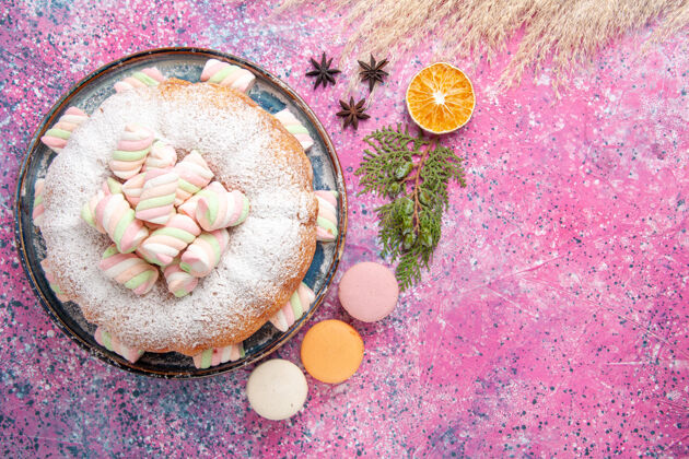 烘焙粉红色表面上糖粉蛋糕和甜棉花糖和麦卡龙的俯视图饼干鲜花新鲜