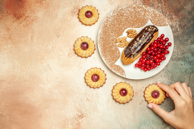 沙子顶视图美味的eclair 带有红色浆果和饼干 甜点甜甜棕色手浆果