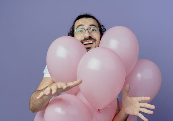 摊开笑容可掬的帅哥戴着眼镜站在气球后面 双手孤立地摊开紫色男人手站着