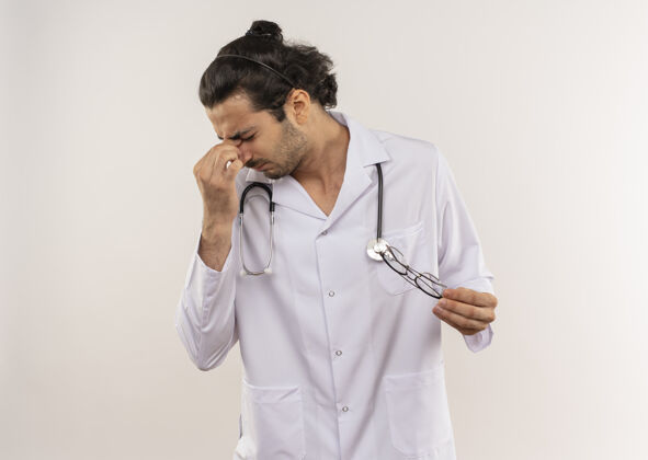 空间疲惫的年轻男医生戴着眼镜 穿着白色长袍 听诊器 手放在白色的额头上听诊器背景复制