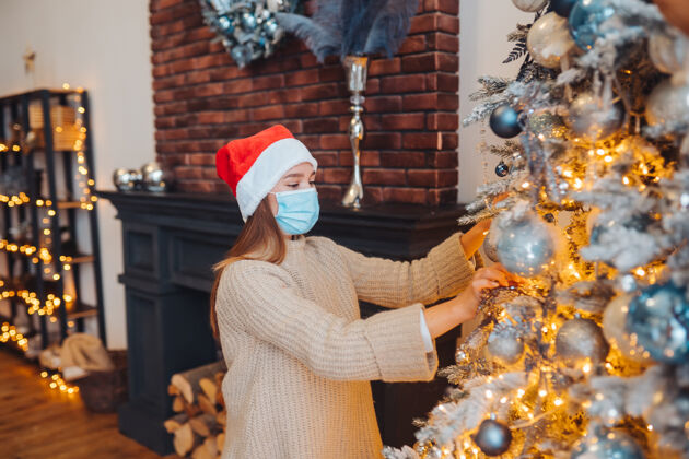 美丽一个年轻的女人用医用面具装饰圣诞树树圣诞面具
