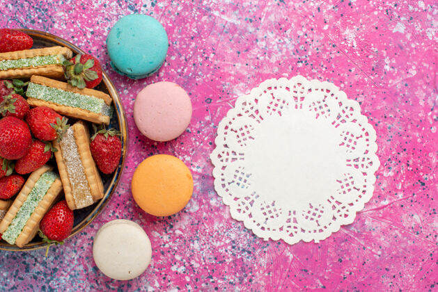 生的美味的华夫饼干俯视图 粉色表面有马卡龙和新鲜的红色草莓华夫饼顶视图新鲜