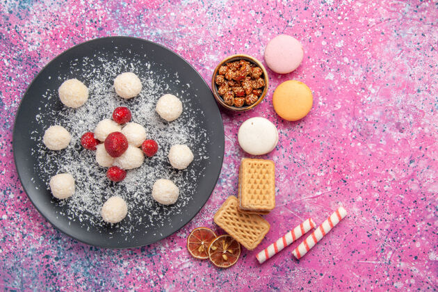 鸡蛋俯瞰美味的椰子糖果甜球与法国马卡龙和华夫饼在粉红色的表面美味顶视图粉末
