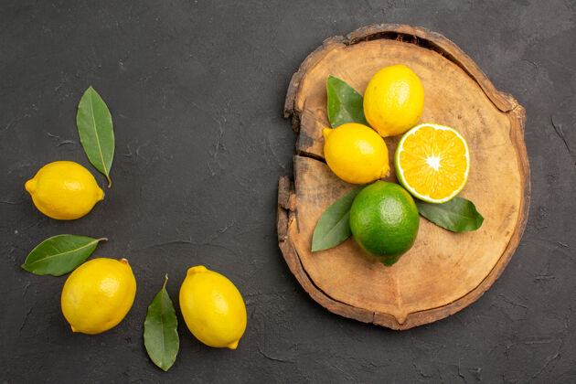 酸橙顶视图新鲜酸柠檬和叶子放在深色的餐桌上水果柠檬黄色的柑橘柠檬顶部健康