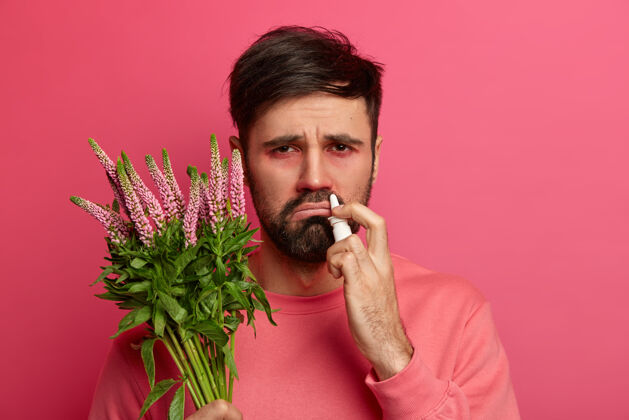 医学过敏性胡须男子持植物 用滴鼻剂治疗喷嚏 对过敏原有不愉快的面部表情 反应 治疗过敏性疾病 遵循过敏学家的建议保健理念发烧痛苦触发器