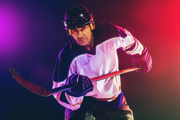 裙子冰球场上的棍子和深色霓虹灯墙的男性冰球运动员黑暗快速冷