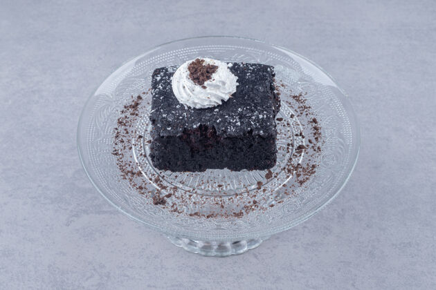甜点在大理石上的玻璃盘子上放一小块巧克力蛋糕奶油美味美味