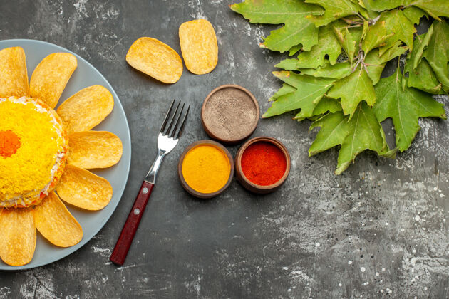 美食沙拉的俯视图在左侧 深灰色的桌子上有香草叉片和叶子食物薯条左边