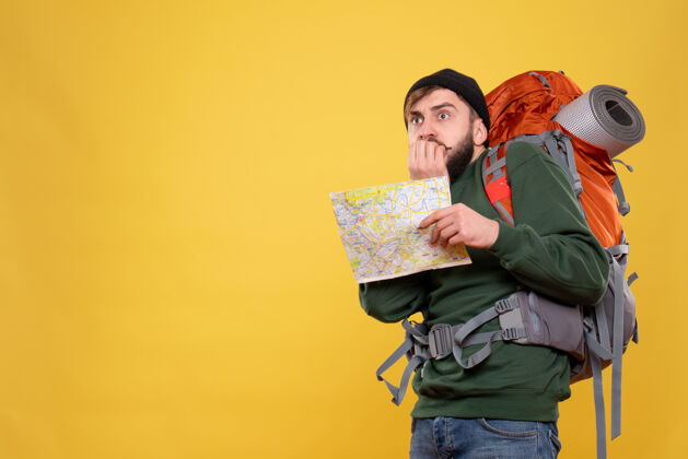 人旅行概念与害怕的年轻人与背包和显示黄色地图成人专业旅行