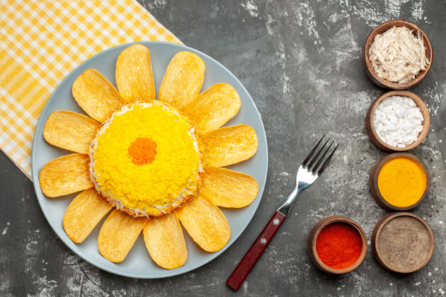 餐巾纸沙拉的俯视图在中间左侧 黄色餐巾在其下方 叉子和草药在深灰色背景的一侧叉子背景柑橘